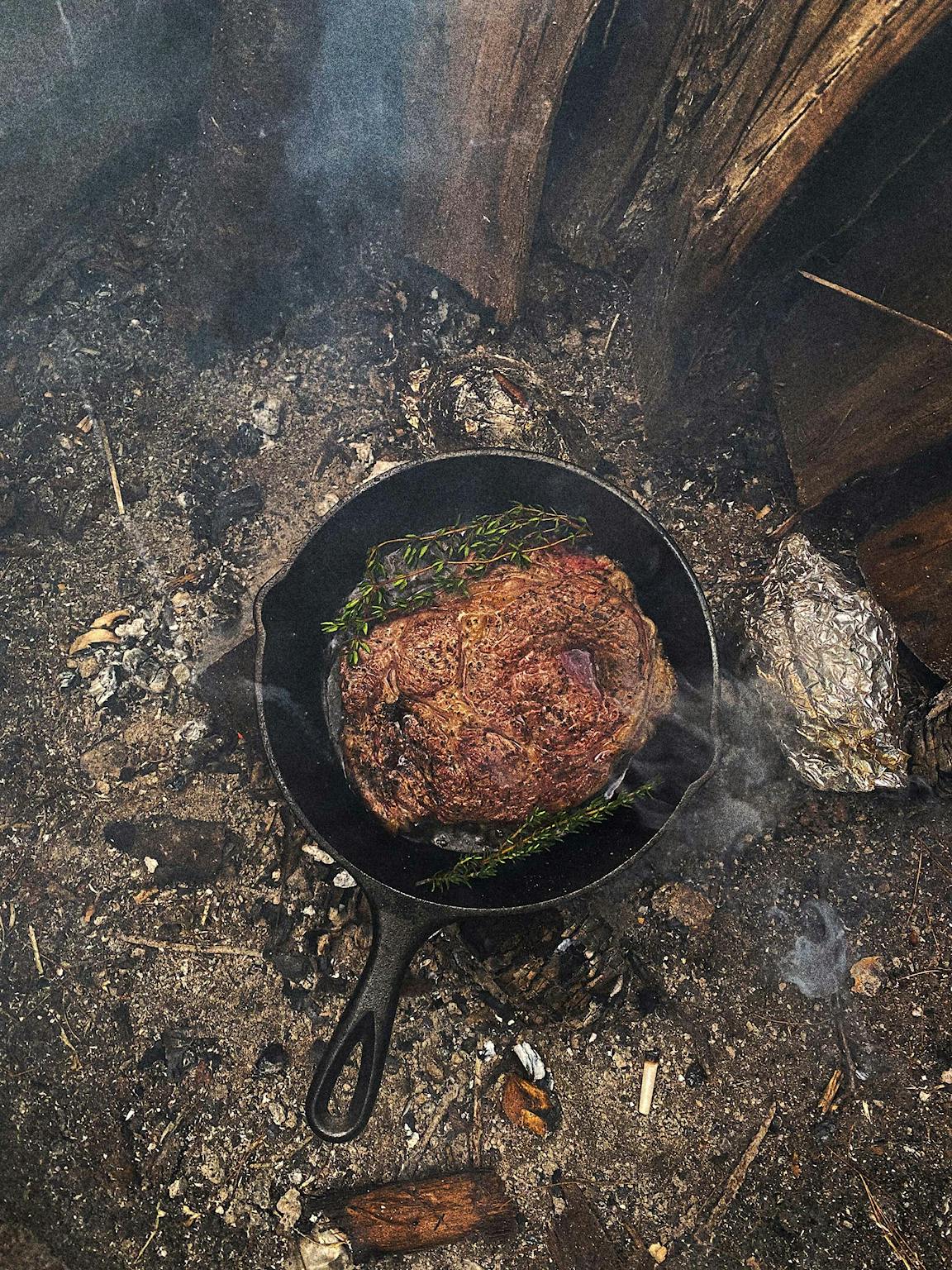A large piece of meat being cooked on a cast-iron skillet.